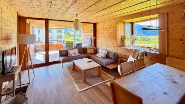L'intérieur d'un chalet en bois, avec un canapé, une table basse et une table à manger.