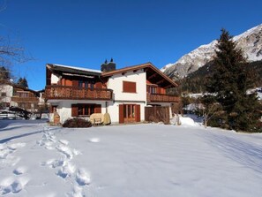 Un chalet à deux étages doté d’un balcon, entouré de neige et de montagnes.