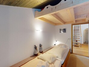A bedroom with a bunk bed, a bedside table, a lamp, and a small wall-mounted picture. - 1607 Palois by Interhome (Lenzerheide)