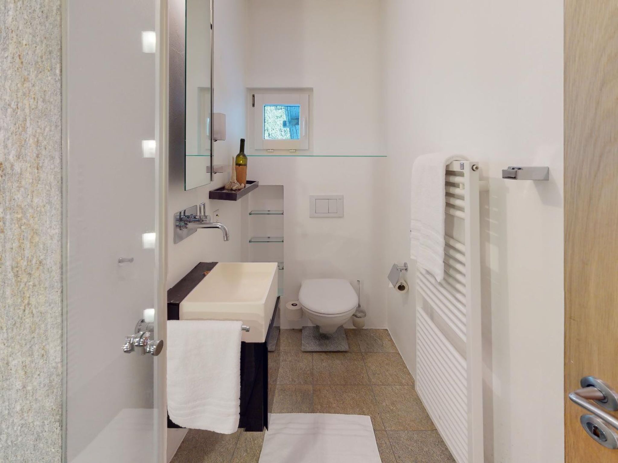 Een kleine badkamer met een wastafel, spiegel, toilet en handdoekhouder.