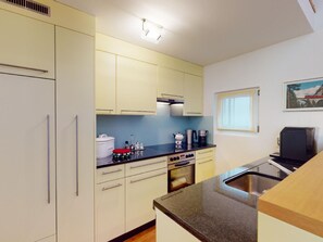 A compact kitchen with a built-in oven, a coffee maker, and a sink. - 1607 Palois by Interhome (Lenzerheide)