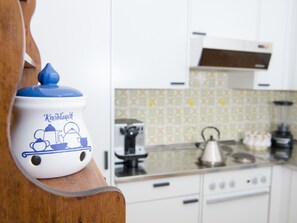 A kitchen with white cabinets, a patterned backsplash, and a blue and white teapot on a wooden shelf. - 1603 Sundrella by Interhome (Lenzerheide)