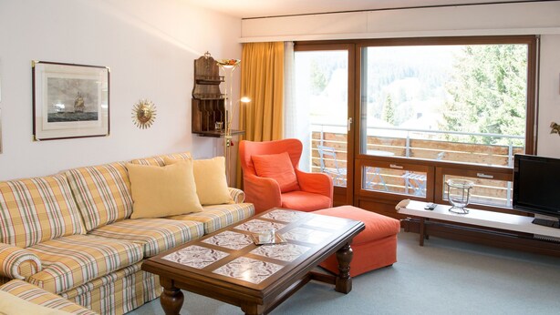 Una sala de estar amoblada con un sofá, un sillón y una mesa.