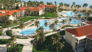 Un complex turístic amb diverses piscines, palmeres i vistes a la platja.