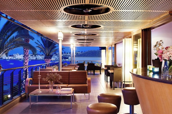 A rooftop bar with a view of the sea, seating arrangements, and a wooden ceiling design. - Spetses (Spetses)