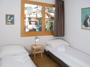 Une chambre avec deux lits, une fenêtre, une table de chevet et une lampe.