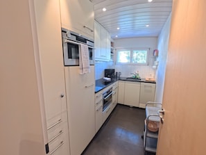 A compact kitchen with white cabinets, a microwave, a coffee maker, and a sink. - 1618 Lai Zentrum by Interhome (Lenzerheide)