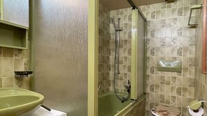 Un baño con bañera, inodoro, lavabo y espejo.