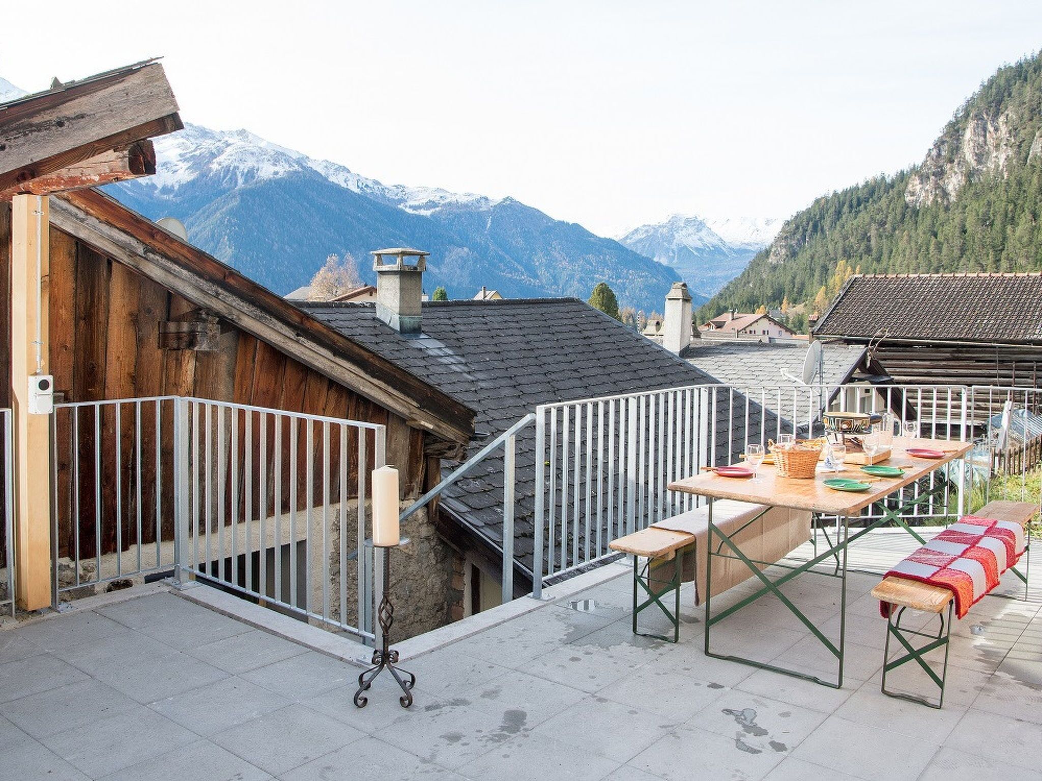 Une terrasse avec une table dressée pour le dîner, offrant une vue sur un paysage montagneux.