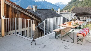 Una terraza con mesa lista para comer, con vistas a un paisaje montañoso.