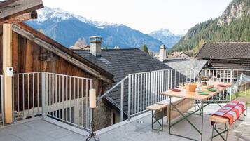Une terrasse avec une table dressée pour le dîner, offrant une vue sur un paysage montagneux.