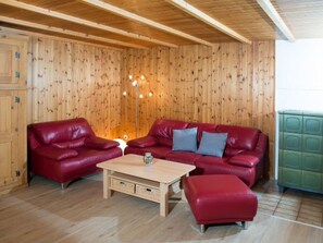 A room with wooden panel walls, a red leather sofa set, a wooden coffee table, and a green cabinet.