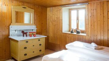 Una habitación de cabaña de madera con una cama, un tocador, un espejo y una ventana.