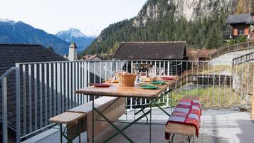 Un espace de restauration en plein air, avec une table et des bancs, offrant une vue sur un paysage montagneux.
