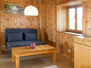 Ein Holzinnenraum mit einer Couch, einem Tisch, einer Lampe und einem Fenster.