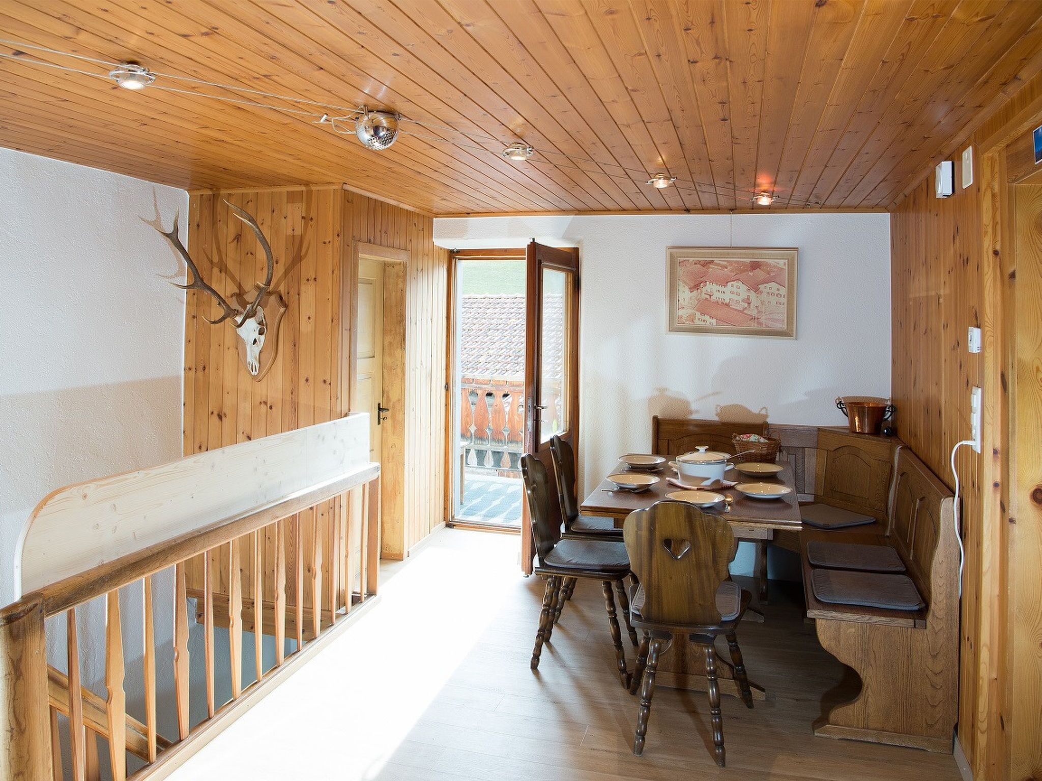 Un interior de madera con una mesa de comedor, sillas y una escalera.