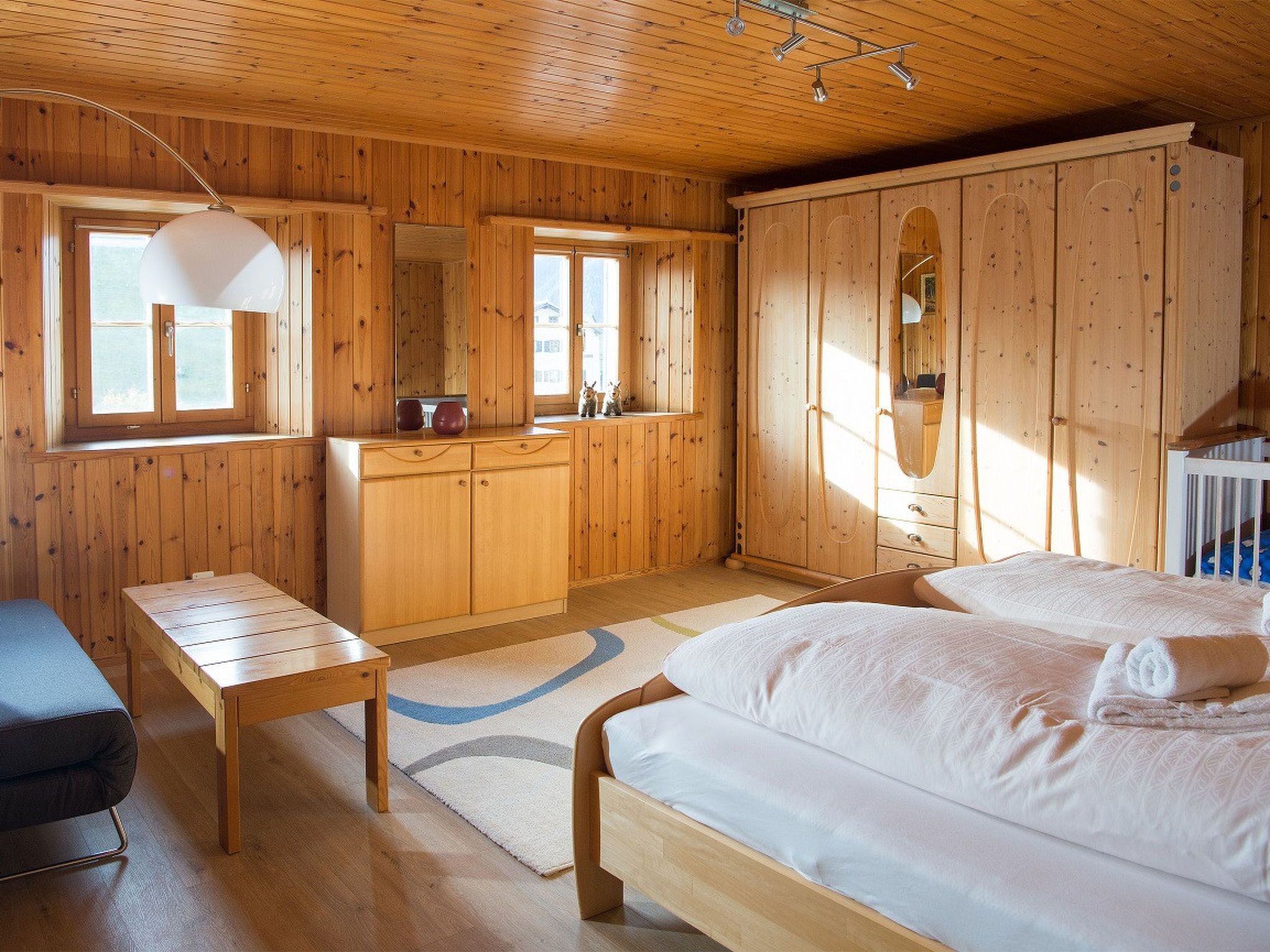Una habitación de cabaña de madera con cama, escritorio, armario y ventana.