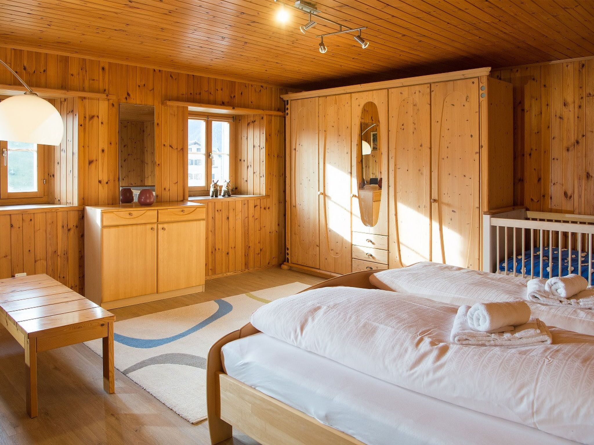 Une chambre dans une cabane en bois, avec deux lits, une commode en bois et une fenêtre.