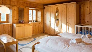 Une chambre dans une cabane en bois, avec deux lits, une commode en bois et une fenêtre.