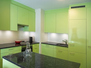 A kitchen with green cabinets, a black countertop, and a red bowl. - 1402 Triangel D by Interhome (Parpan)