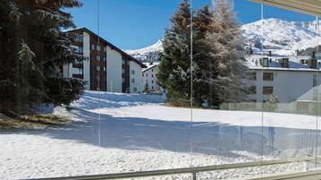 Schneebedeckte Landschaft mit Gebäuden und Bäumen, sichtbar durch ein Fenster.