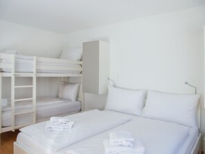 A room with bunk beds and a single bed, both with white bedding and pillows. - 1402 Triangel D by Interhome (Parpan)