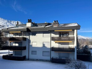 A modern multi-story building with balconies, a garage, and a view of snow-covered mountains. - 1402 Triangel D by Interhome (Parpan)