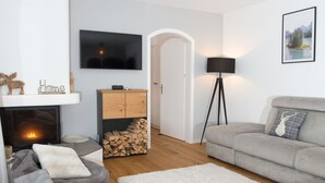 Een moderne woonkamer met een open haard, een televisie, een bank en een lamp.