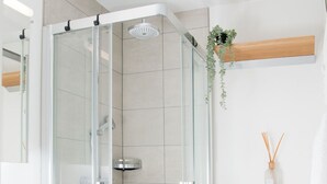 Een moderne badkamer met een glazen douchecabine, een wit wastafelmeubel en een toilet.