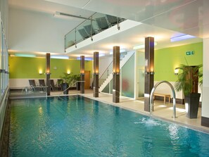 An indoor swimming pool with clear water, surrounded by walls with green panels and modern lighting fixtures. - 1610 Schweizerhof 242 by Interhome (Lenzerheide)