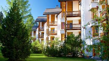 A multi-story hotel with balconies, surrounded by greenery and trees.
