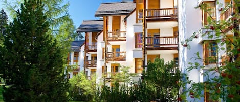 A multi-story hotel with balconies, surrounded by greenery and trees.