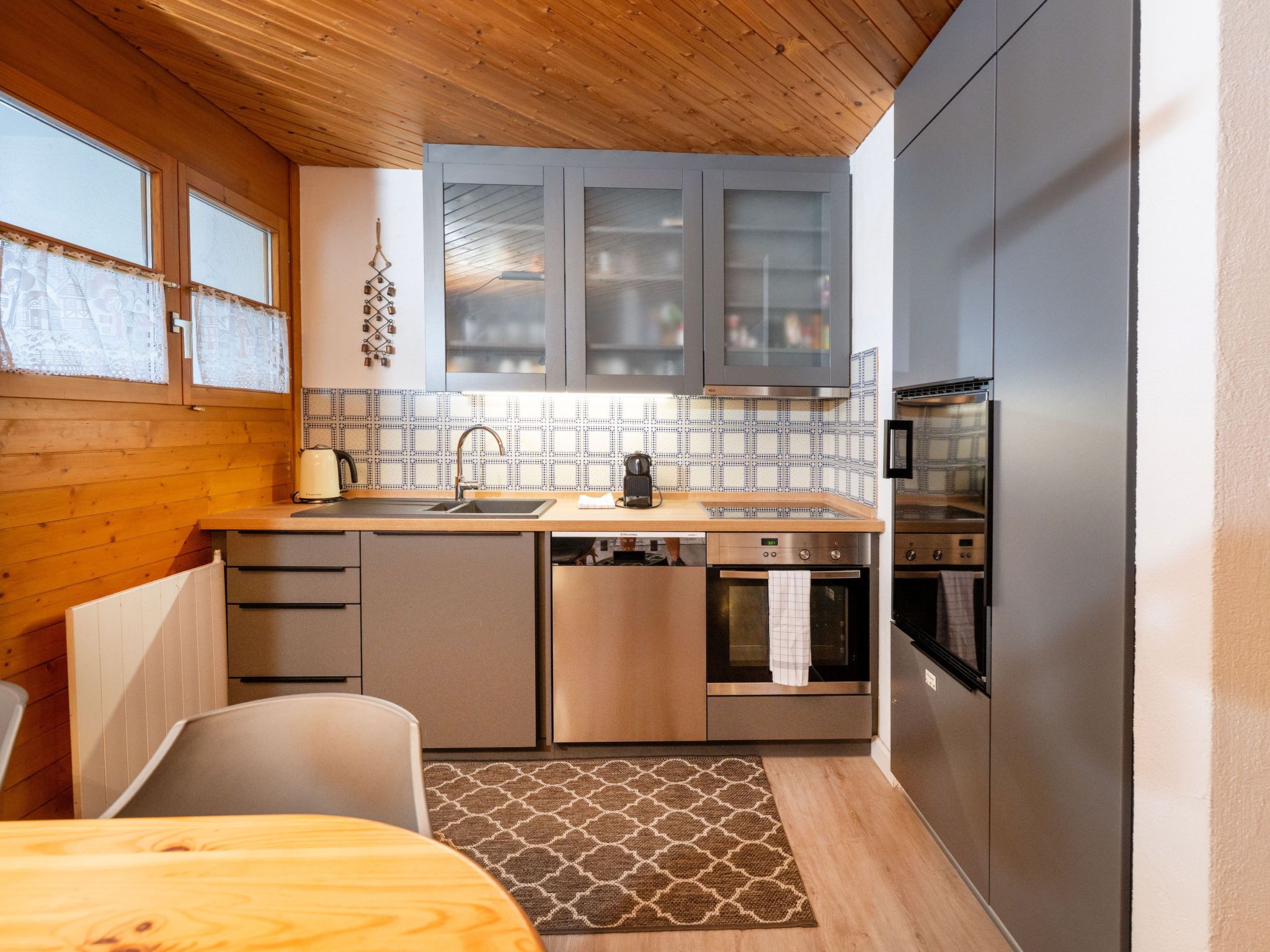 Una cucina compatta con soffitto in legno, un lavello, un fornello e un frigorifero.