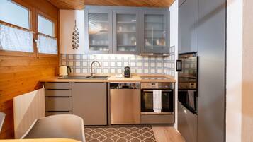 Una cucina compatta con soffitto in legno, un lavello, un fornello e un frigorifero.