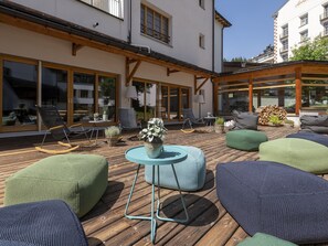 An outdoor seating area with wooden flooring, cushioned seating, and a central table. - 1609 Schweizerhof 604 by Interhome (Lenzerheide)