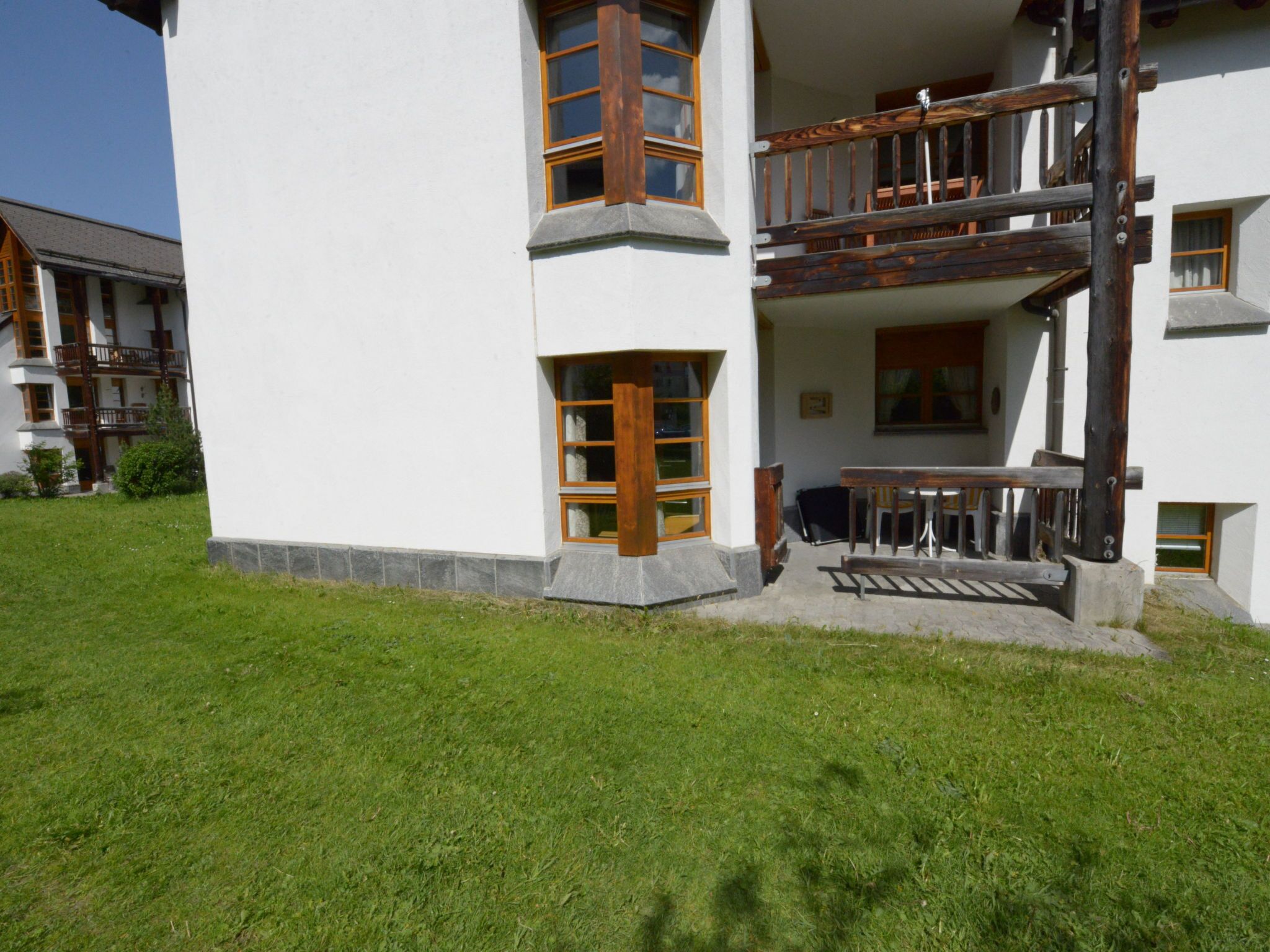 Ein mehrgeschossiges Gebäude mit einem Balkon, einem Steinfundament und einem Rasen.
