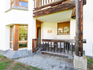 Une entrée d’immeuble avec un portail en bois, un banc et une petite table.