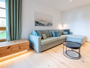 Un salon moderne avec un canapé d’angle, une table basse ronde et un banc en bois.