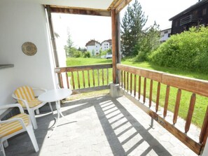 A covered outdoor area with a wooden railing, a small table, and two striped chairs. - Schweizerhof 604 Lenzerheide by Interhome (Lenzerheide)