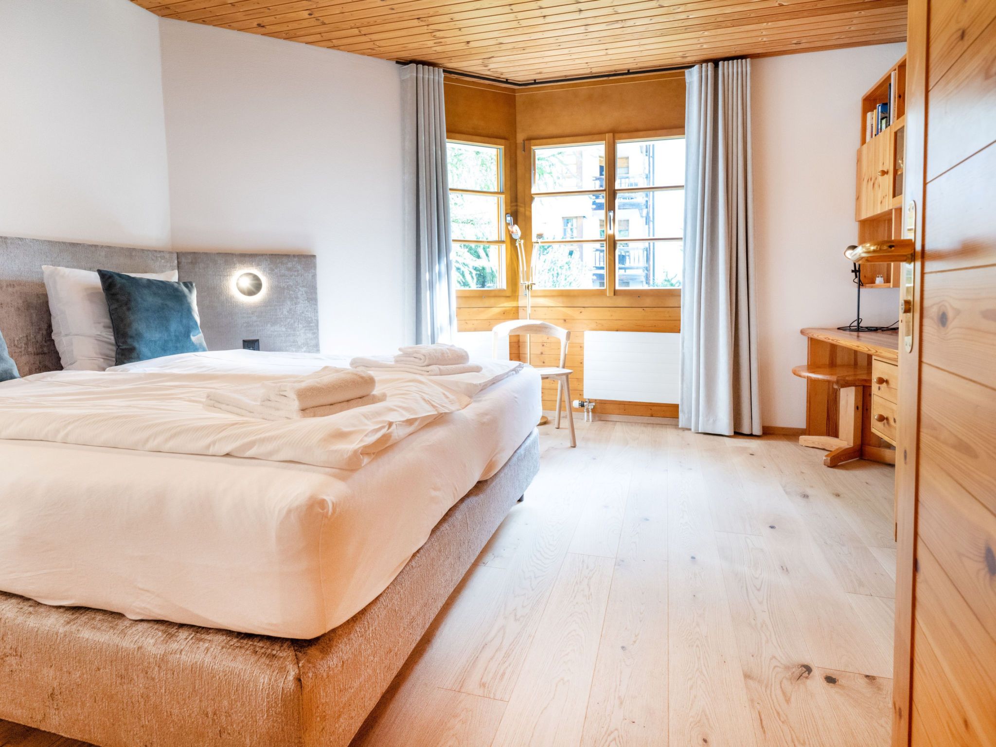 Een moderne slaapkamer met een groot bed, een bureau en een stoel.