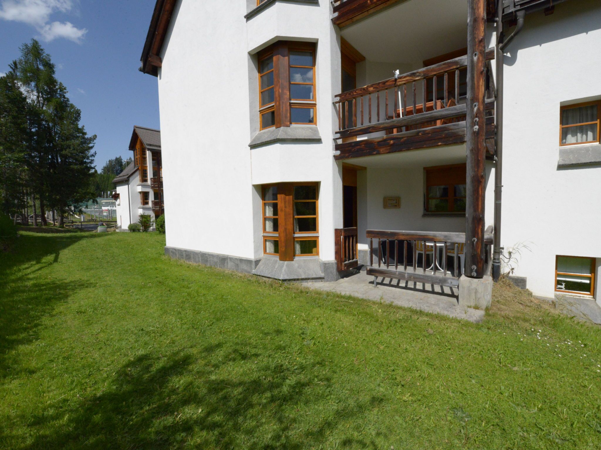 Ein mehrstöckiges Gebäude mit einem Balkon, einem Rasen und blauem Himmel.