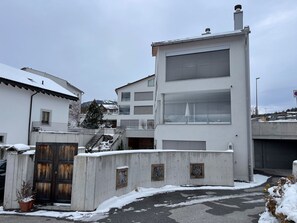 Moderni rakennus, jossa on autotalli, portaikko ja lumipeitteinen maa.