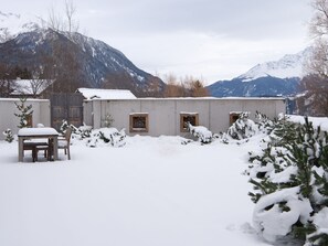 A snow-covered outdoor area with a table and chairs, a wooden fence, and a building with windows. - 1907 Valmala by Interhome (Lantsch)