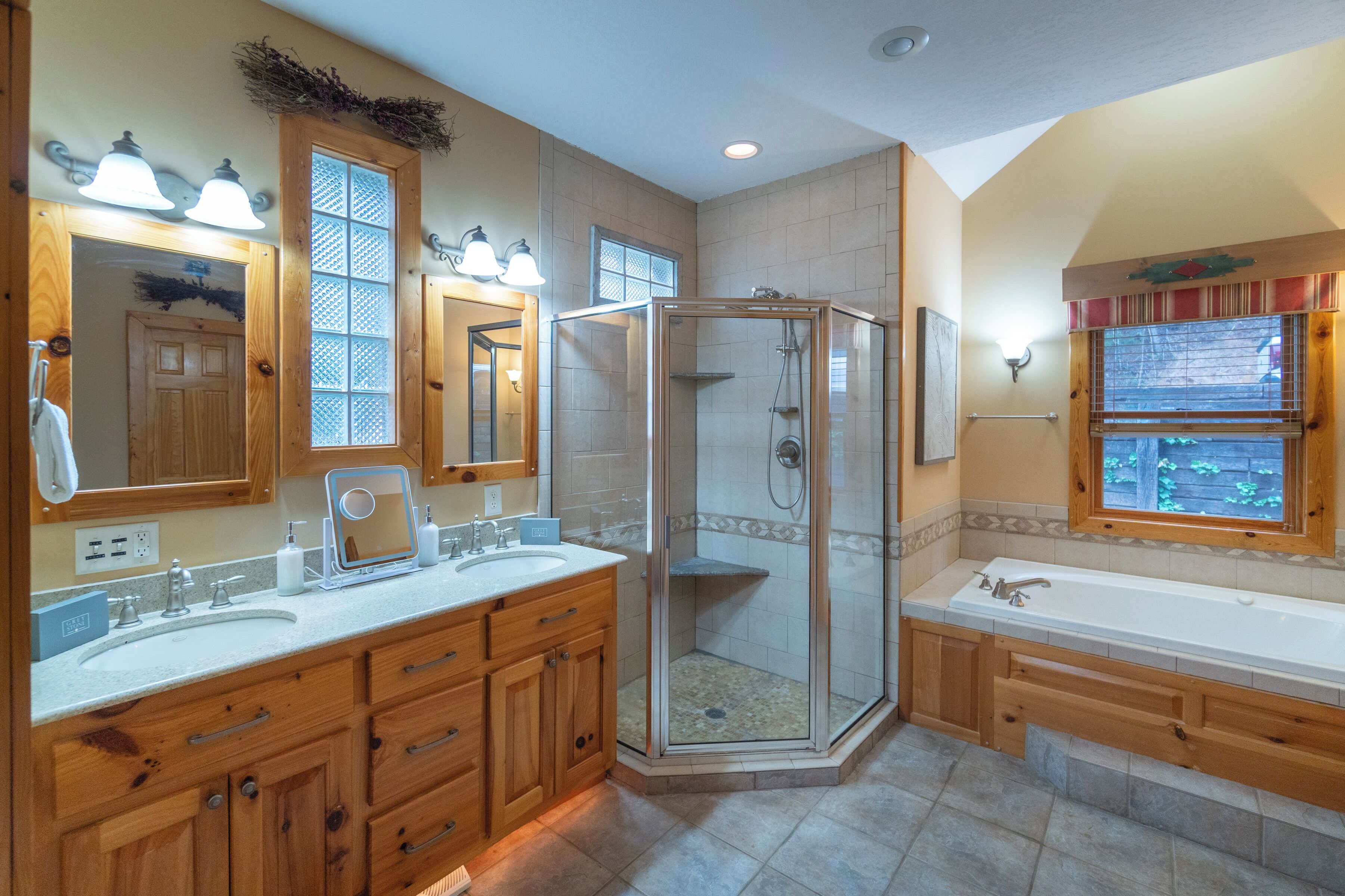 A modern bathroom with a double sink, a walk-in shower, and a large bathtub.