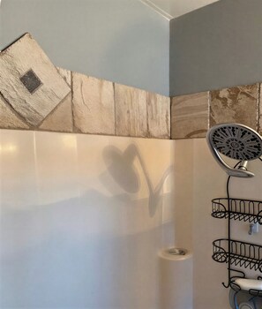 A shower with a metal rack and a heart-shaped shadow on the wall.