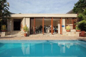 A swimming pool with a building in the background. - The Wilderness Hotel (Wilderness)