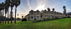 A hotel with multiple buildings, a well-maintained lawn, and palm trees. - The Wilderness Hotel (Wilderness)
