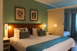 A hotel room with a bed, bedside tables, and two framed pictures on the wall. - The Wilderness Hotel (Wilderness)