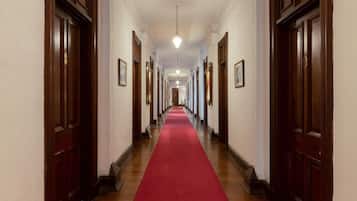 A long hallway with wooden doors on either side and a red carpet.