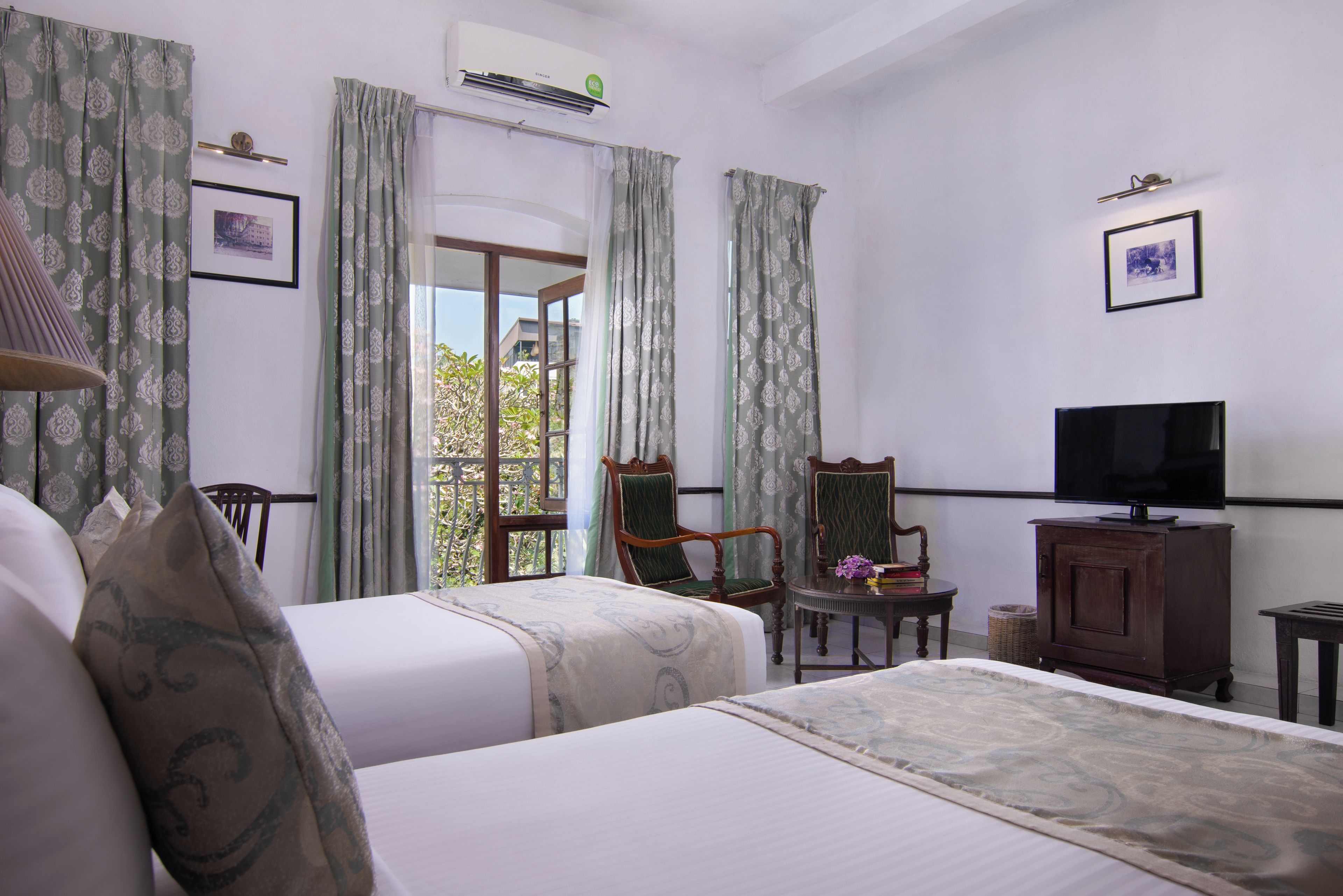 A hotel room with two beds, a television, a chair, and a small table.